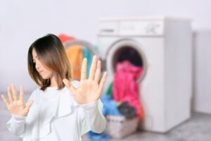 donna che fa stop con le mani e bucato in lavatrice
